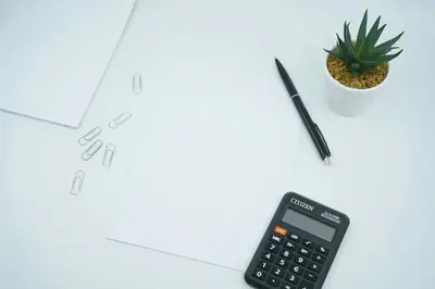 Kalkylator, penna och papper som illustration till en resebudget