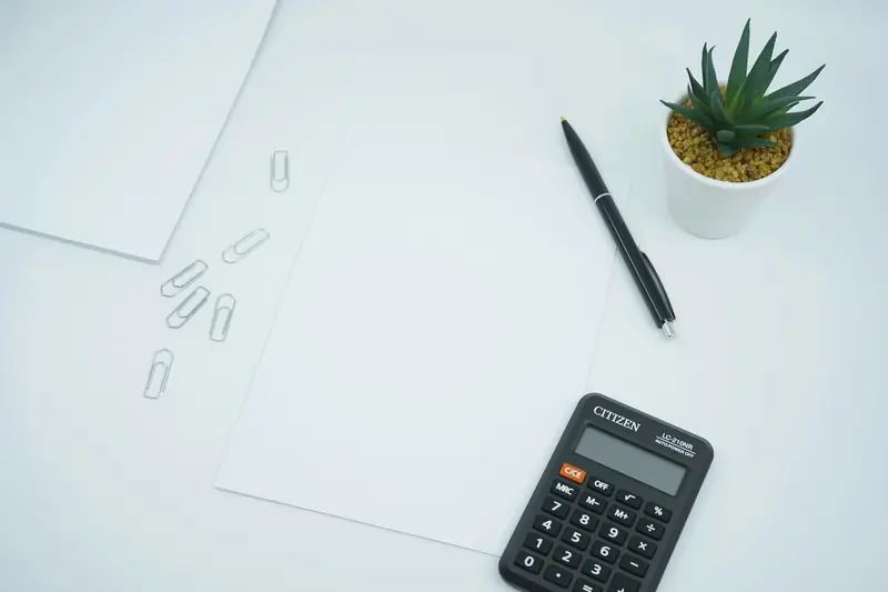 Kalkylator, penna och papper som illustration till en resebudget