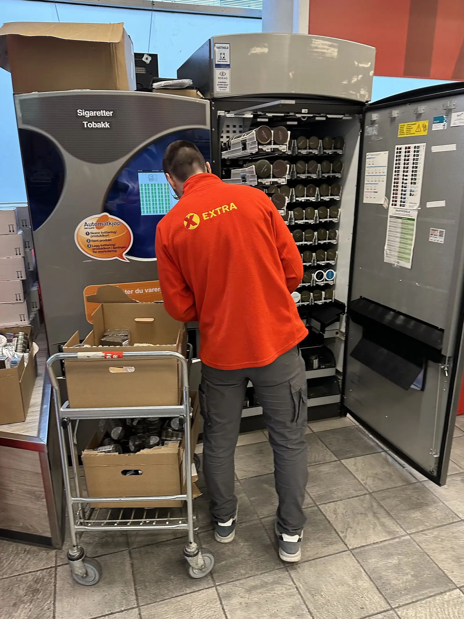 En butiksanställd fyller på snus i en tobaksautomat i Stavanger