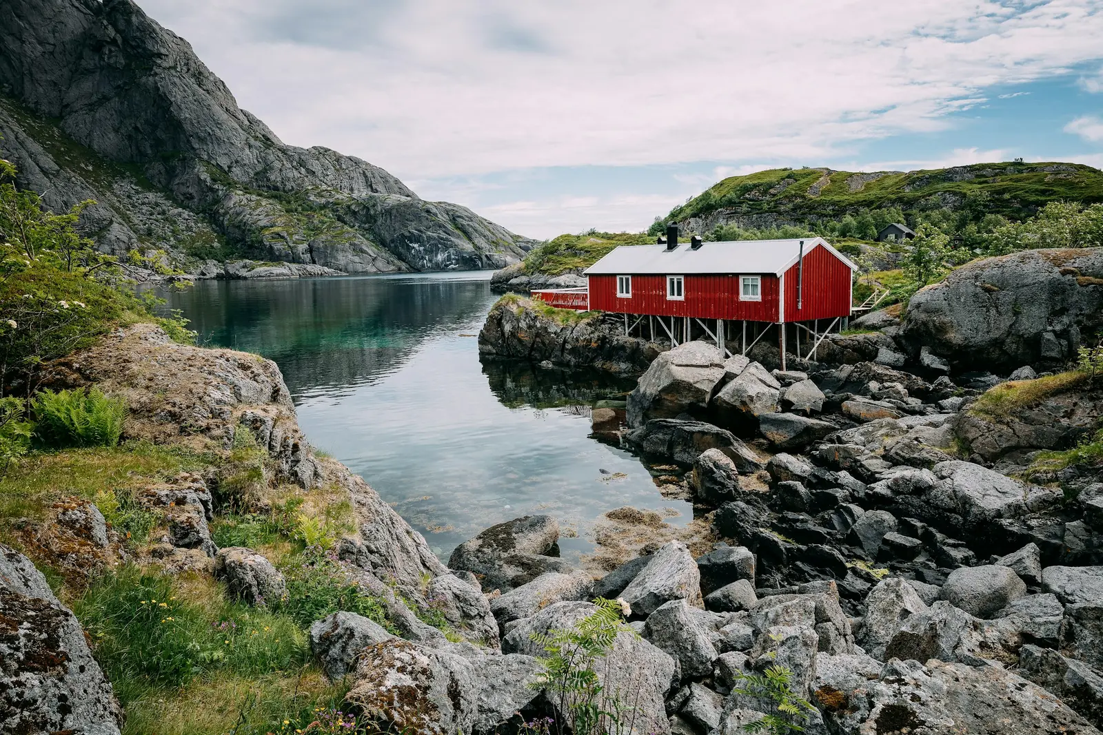 Röd fiskarstuga vid vattnet i Nusfjord på Lofoten