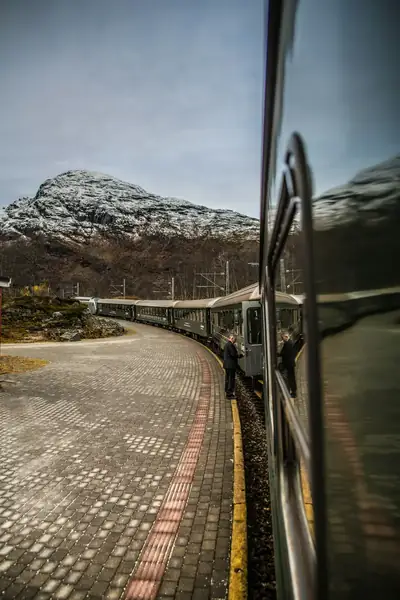 Grönt tåg vid Flåm med höstlandskap och fjäll i bakgrunden