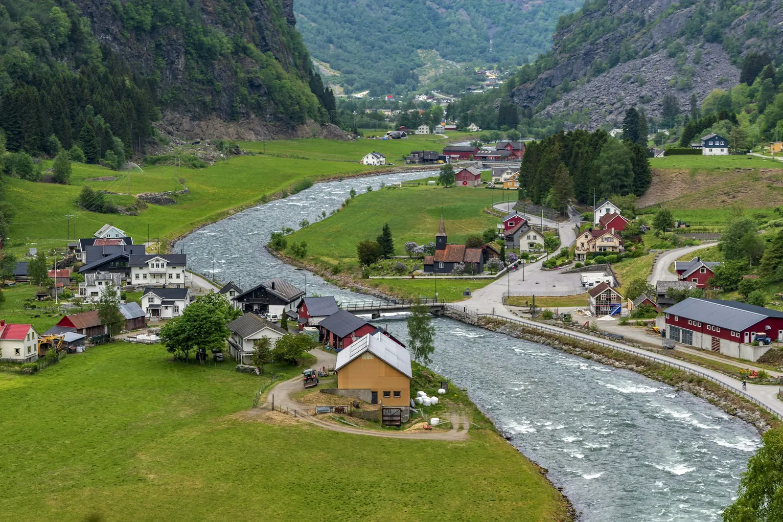 Grön dalgång med älv och bebyggelse i Flåmsdalen
