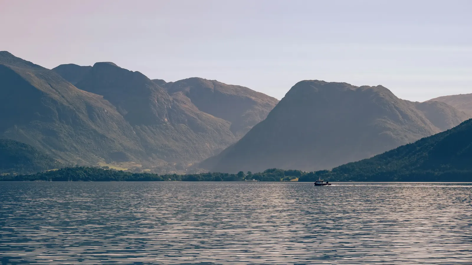 Båt på Hardangerfjorden med fjäll i mjukt kvällsljus