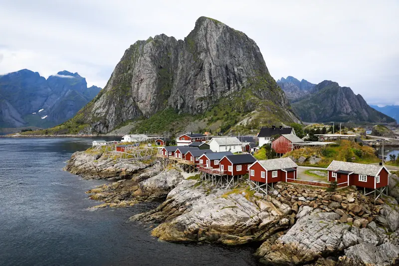 Röda rorbuer vid vattnet och branta fjäll i Lofoten