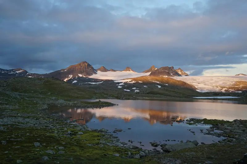 Smørstabbtindan speglar sig i en sjö vid Sognefjellet i kvällsljus
